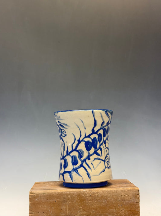 Ceramic vase with blue floral design on a wooden block against a gray background