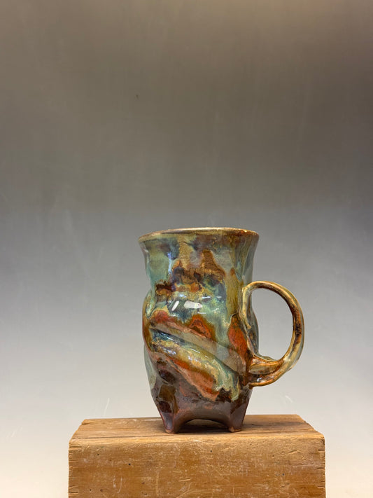 Ceramic mug with a textured surface on a wooden block against a plain background